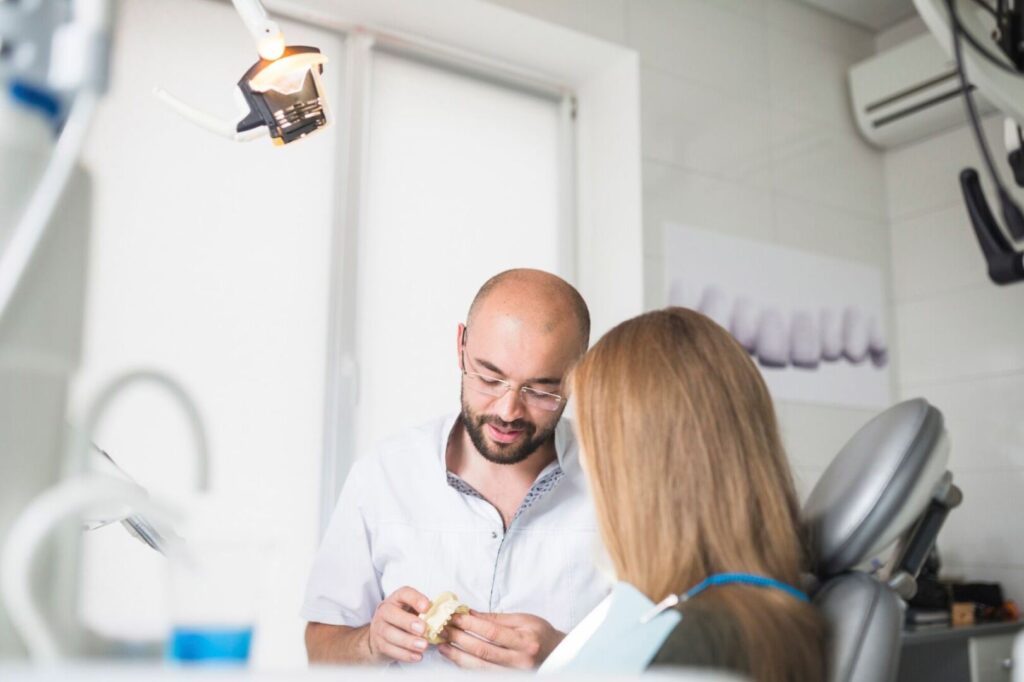 female patient front male dentist holding dental jaw 23 2147862031